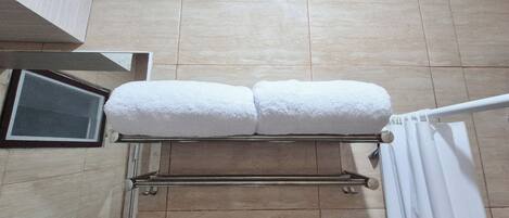 A bathroom with a towel rack holding two white towels.