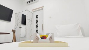 Une chambre d’hôtel comprenant un lit, une table de chevet, un téléviseur fixé au mur et une armoire avec un miroir.