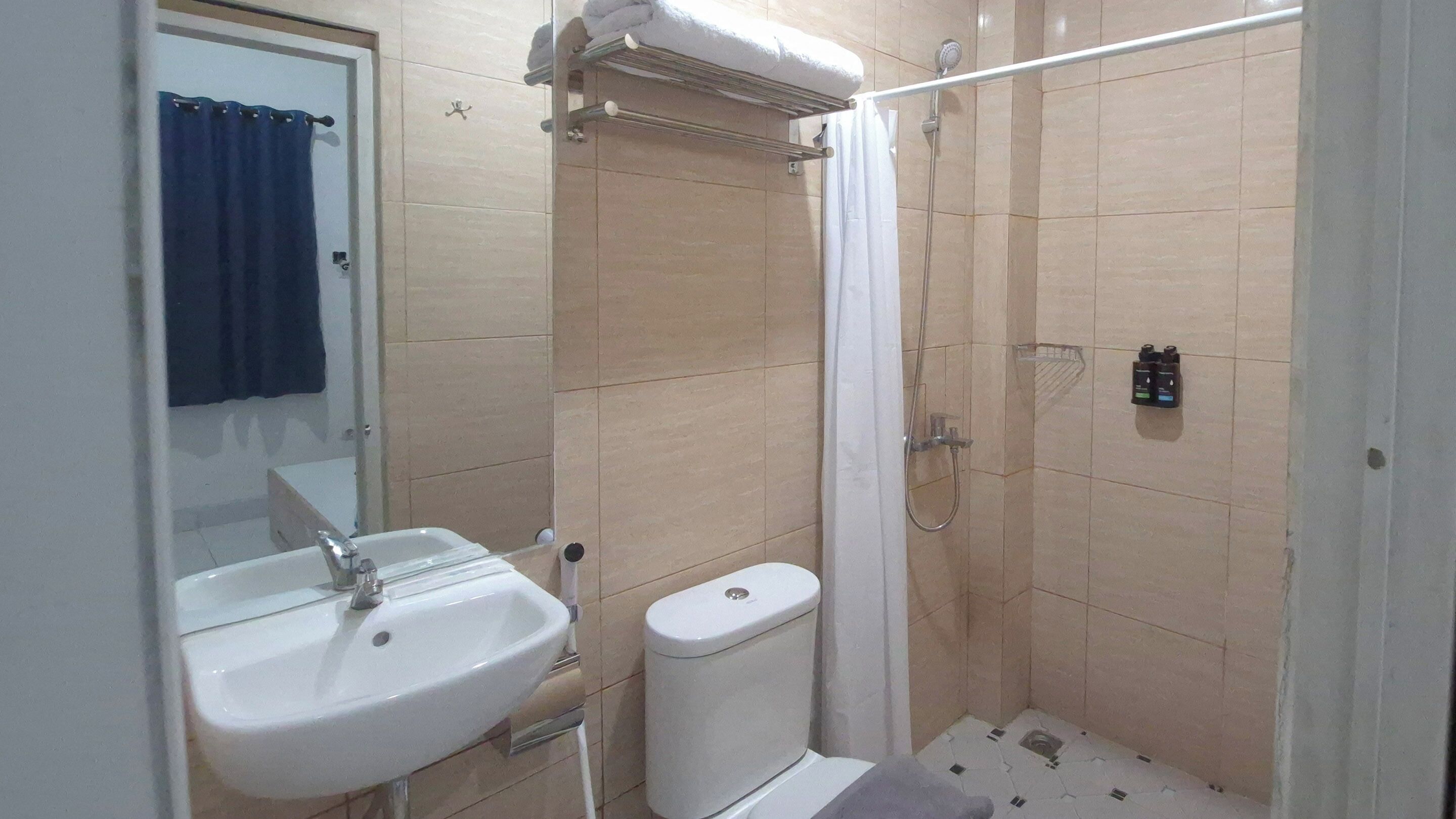 A bathroom with a sink, toilet, shower, and a towel rack.