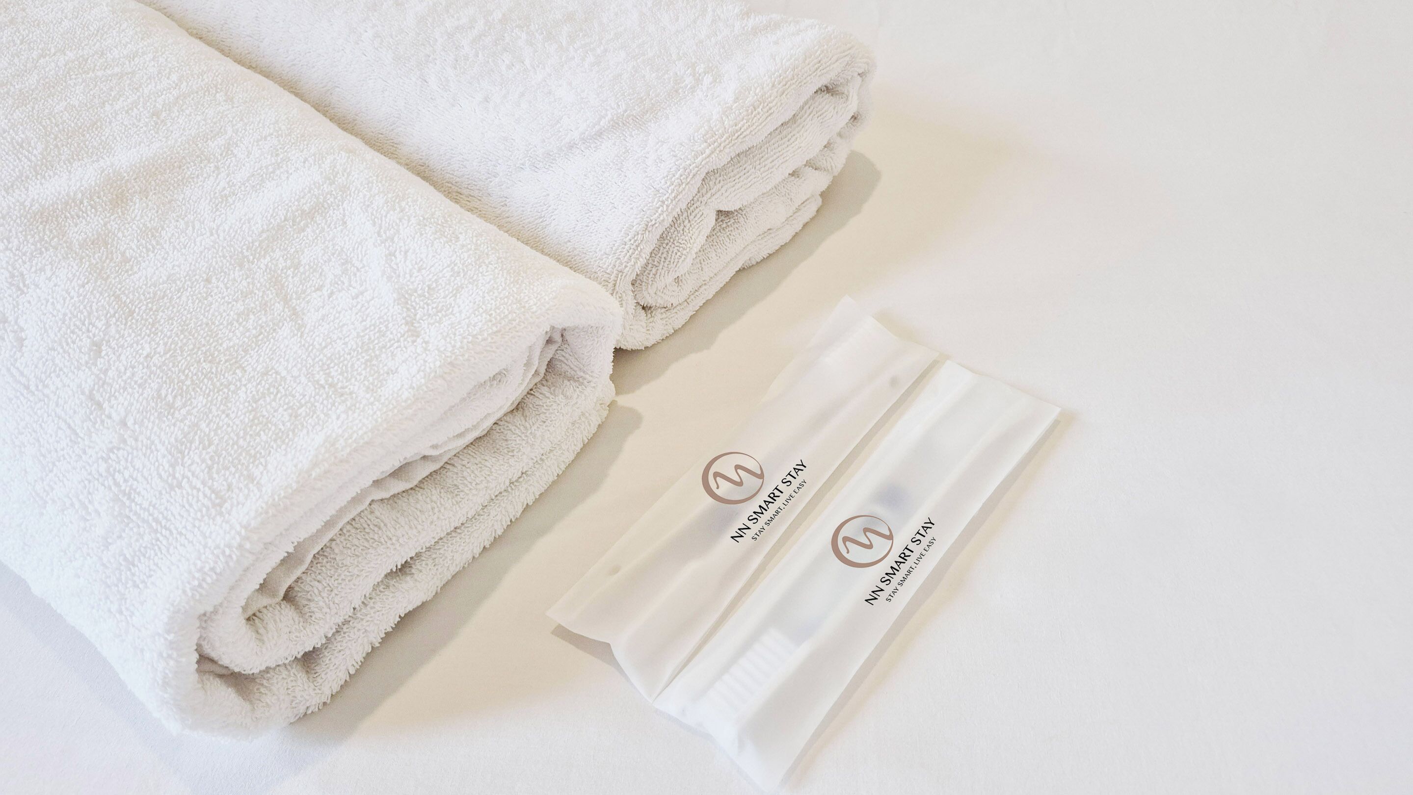 Two neatly folded white towels and a white package with a logo and text.