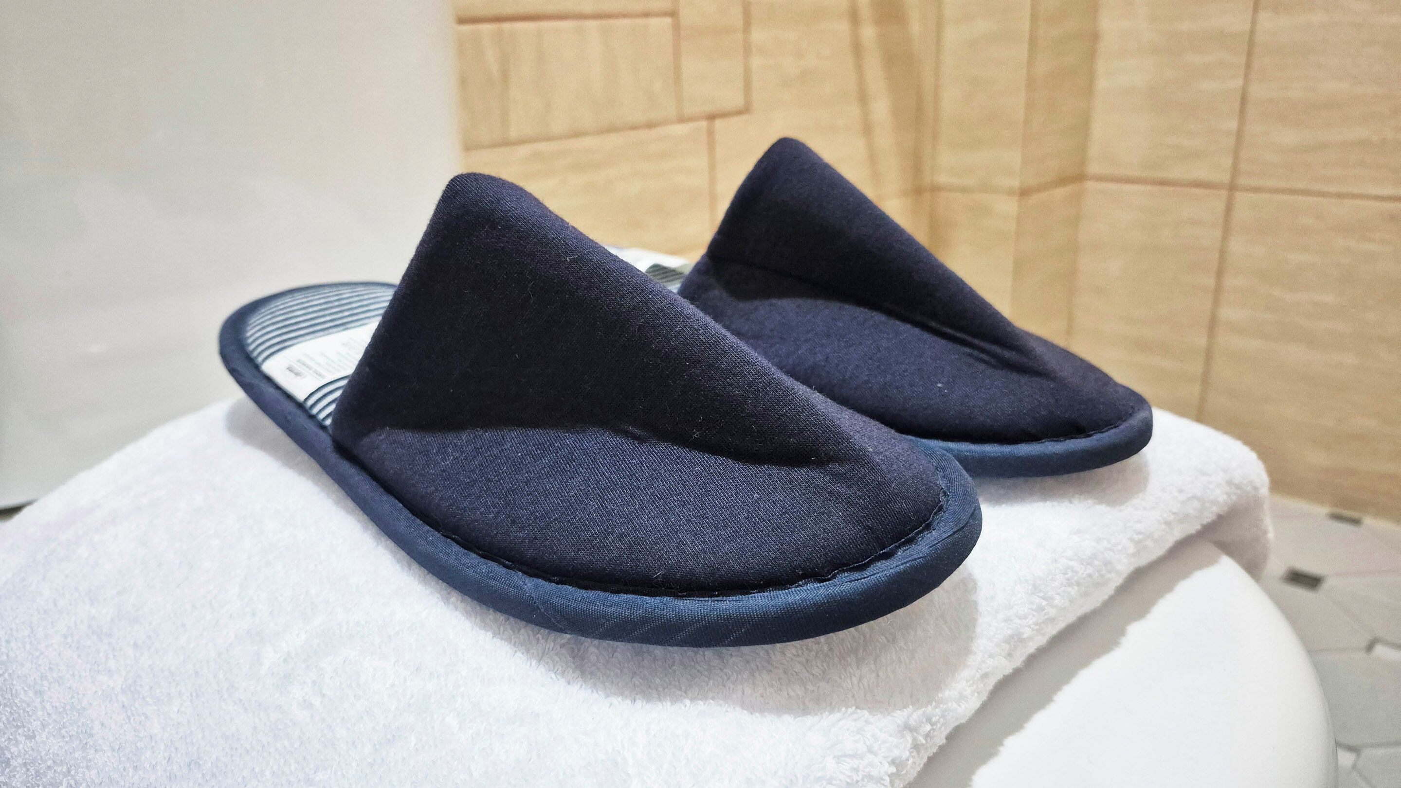 A pair of dark blue slippers on a white towel.