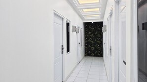 Un couloir aux murs et aux portes blancs, doté d’un sol carrelé.