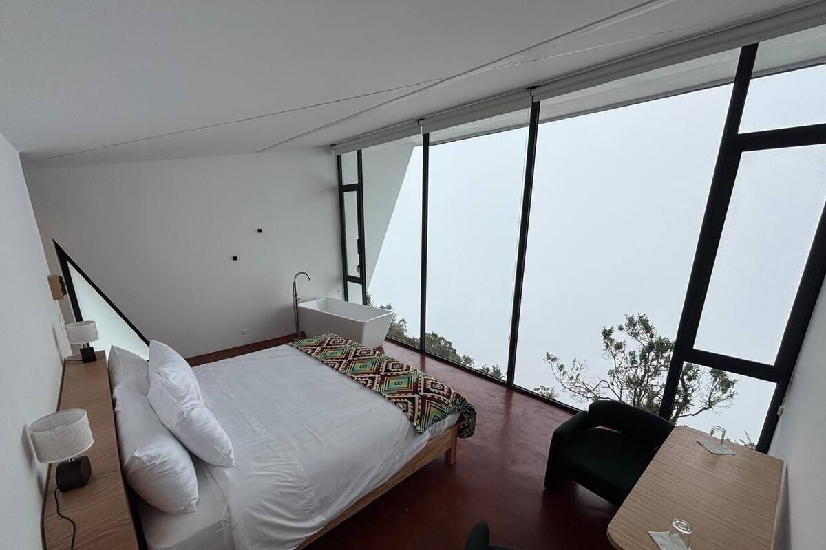 Un dormitorio moderno con una cama grande, un escritorio y vistas al exterior.