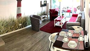 Una sala de estar con televisor, sofá rojo y una mesa de comedor preparada para cuatro.