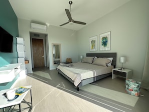 Ein modernes Schlafzimmer mit Bett, Nachttischen, einem Schreibtisch und einem Deckenventilator.