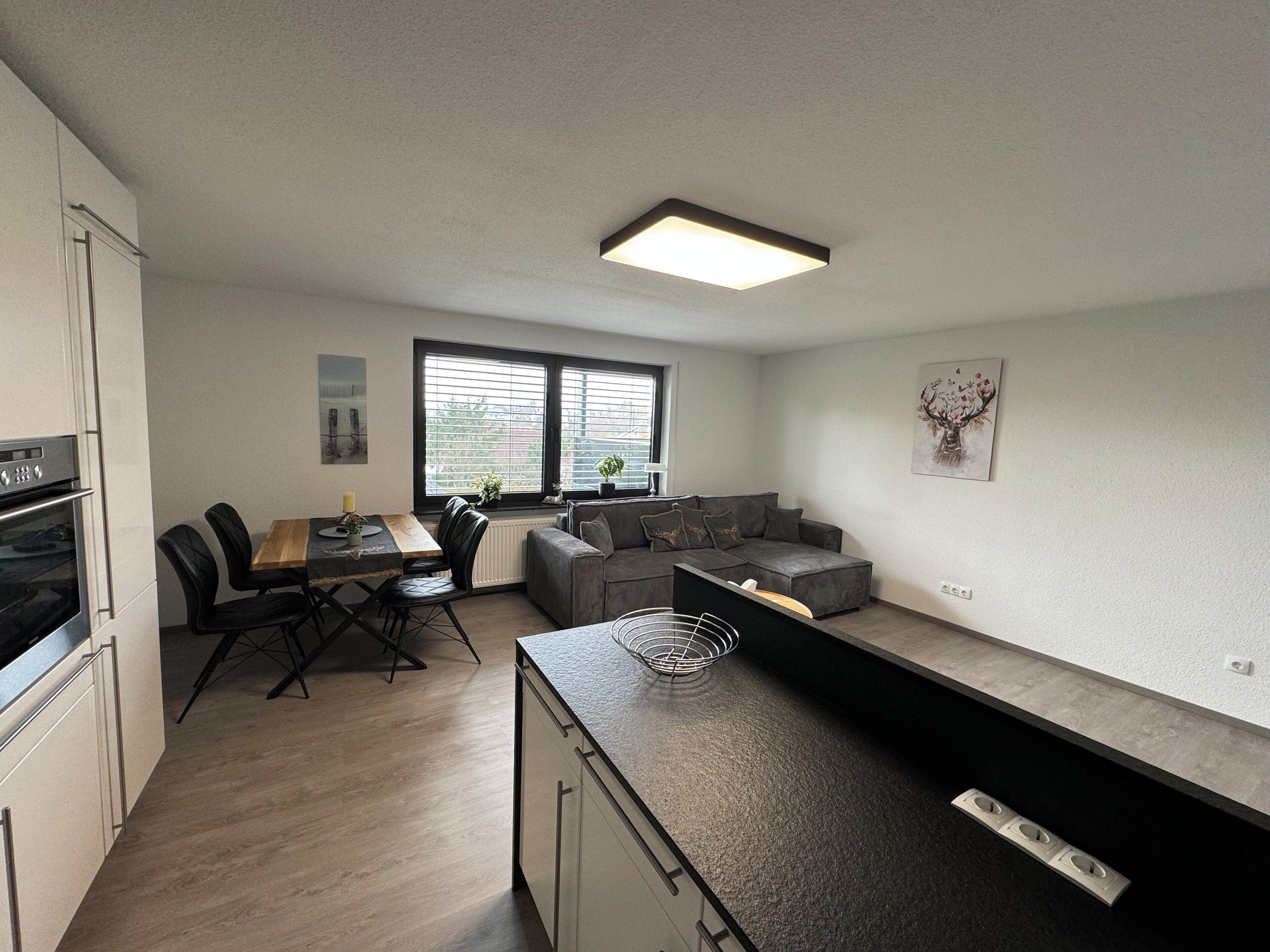 A modern kitchen with a dining area, a built-in sofa, and a large window providing natural light.