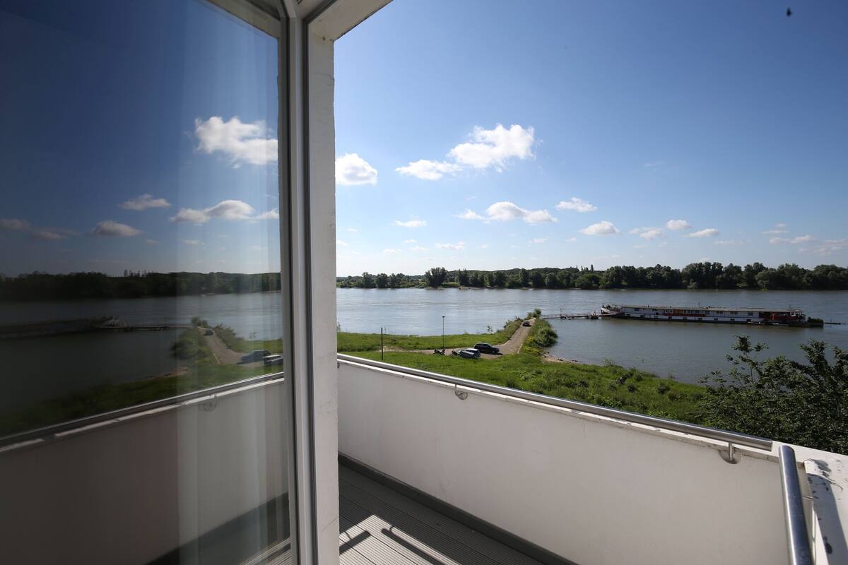 A view from a balcony overlooking a river with a boat docked on the right.