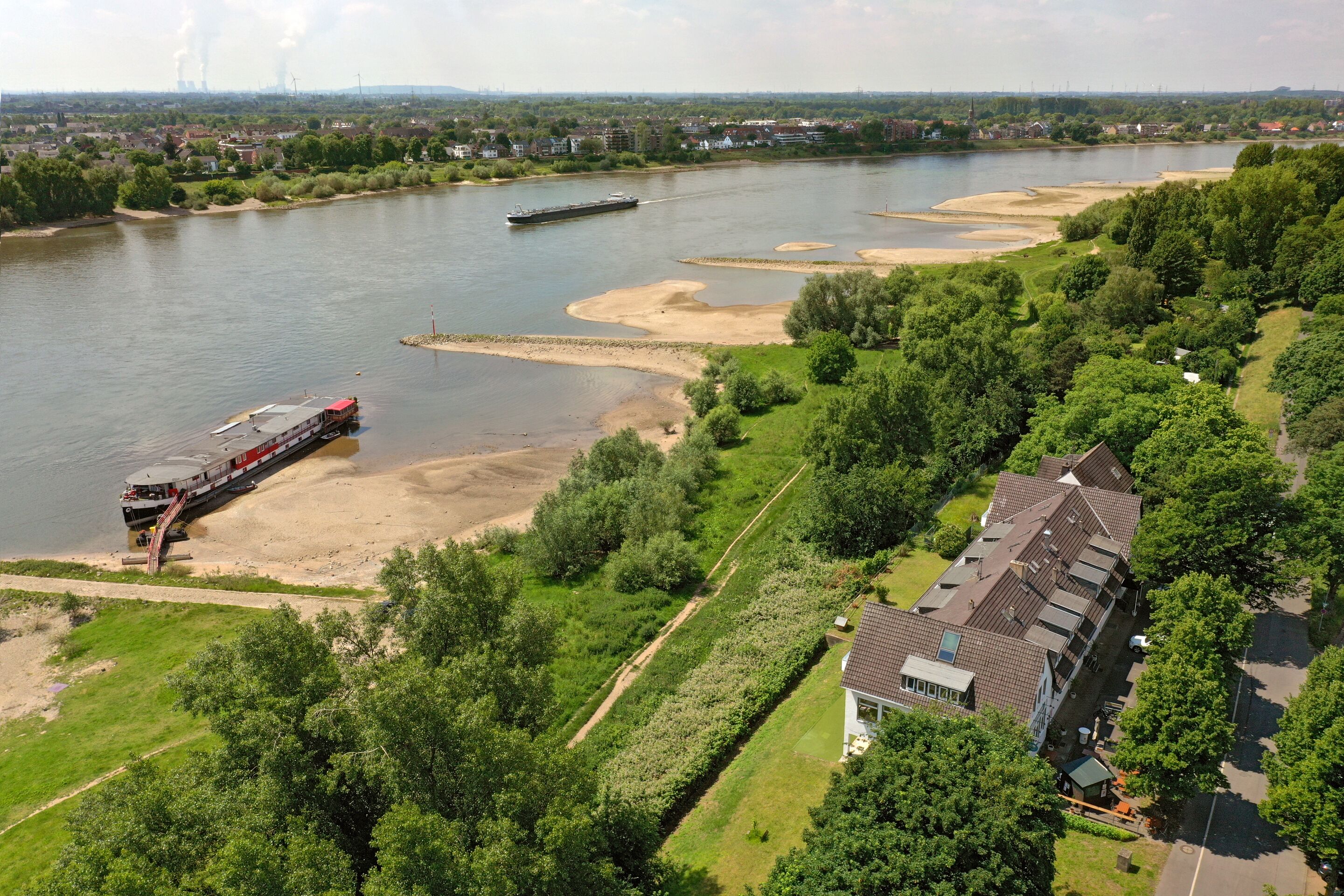 Une rivière avec un bateau, un quai et un bâtiment doté d’un toit en pente.