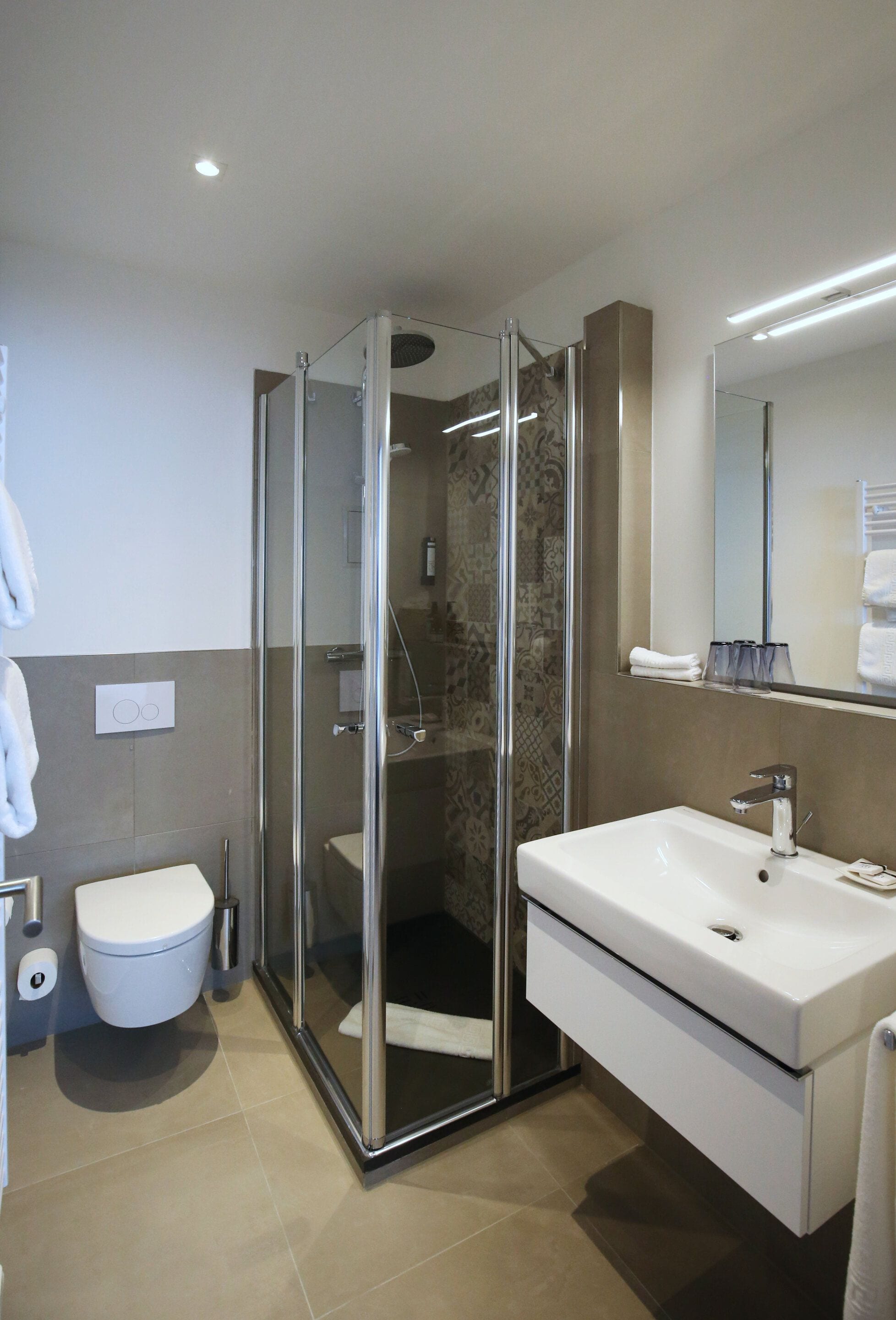 A modern bathroom with a glass-enclosed shower, a white sink, and a toilet.
