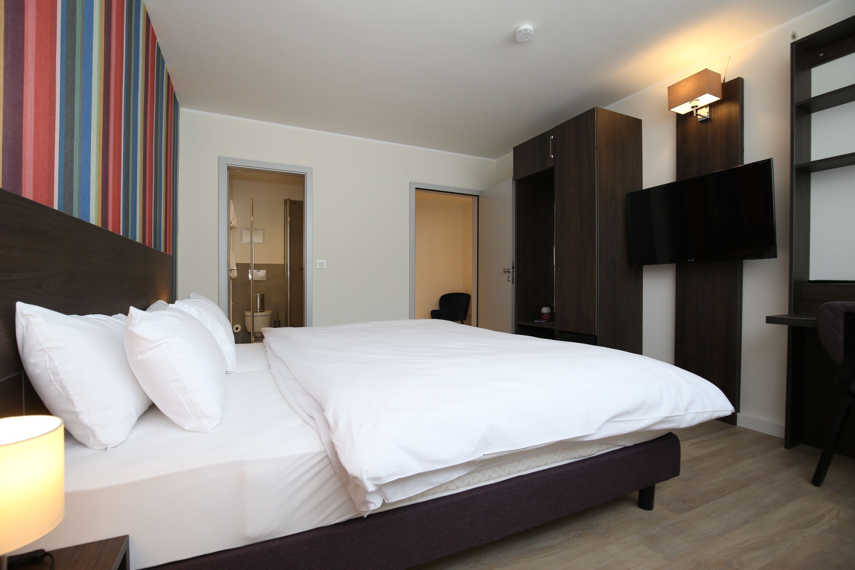 Une chambre d’hôtel moderne dotée d’un grand lit, d’un téléviseur à écran plat et d’une armoire.