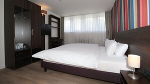 Une chambre d’hôtel avec un grand lit, une armoire, un bureau avec une chaise et une télévision.