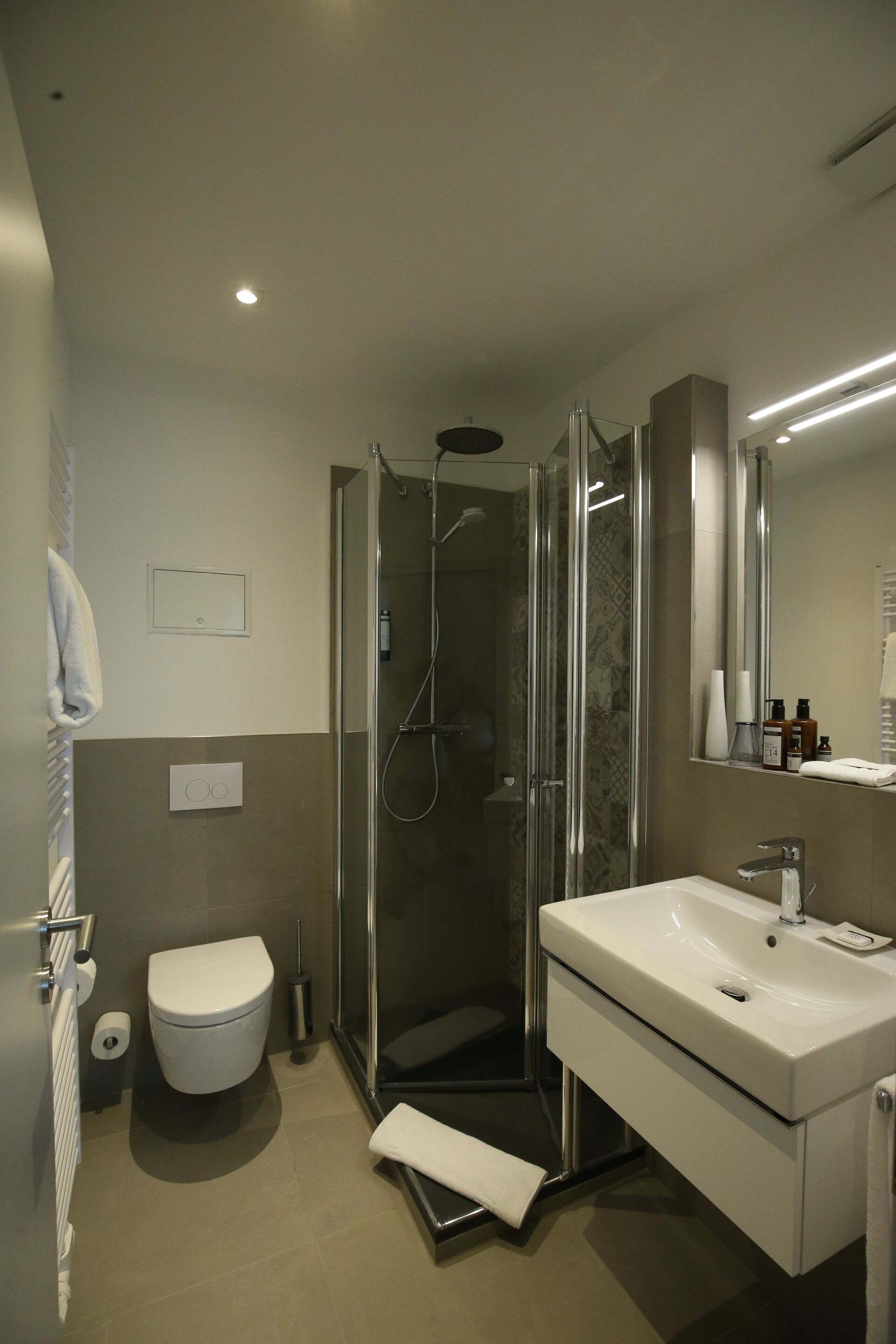 A modern bathroom with a glass-enclosed shower, a white sink, and a toilet.
