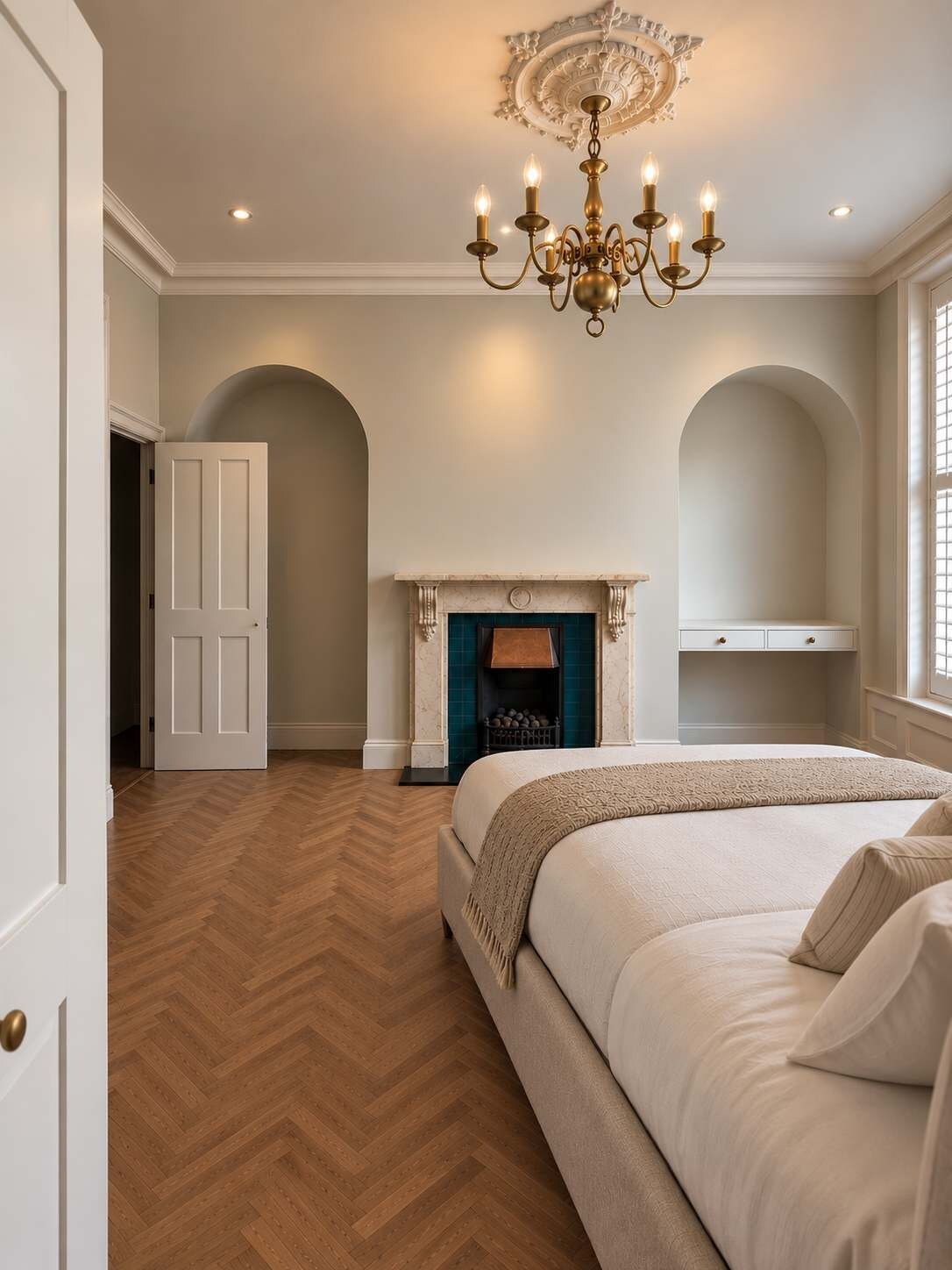 A bedroom with a large bed, a fireplace, and a chandelier.
