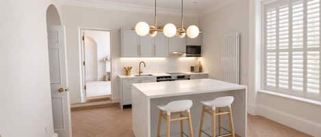 A modern kitchen with a central island, pendant lighting, and a view to the outside.