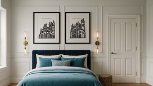 Un dormitorio con una cama, dos cuadros enmarcados, una mesita de noche y una puerta.