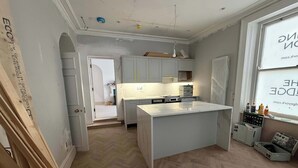 Una cocina moderna con armarios blancos, una isla central y un suelo con estampado de espiga.