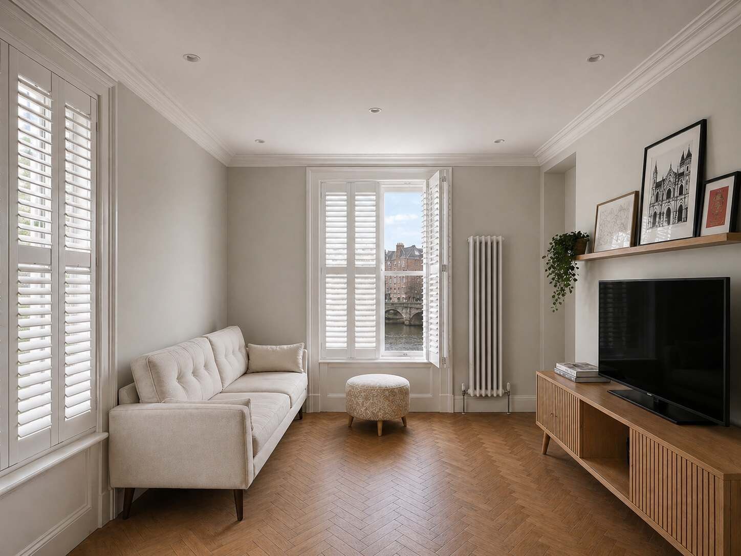Una sala de estar moderna con sofá, reposapiés, televisor y radiador.