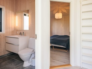 A modern bathroom with a white sink, toilet, and mirror. - 4 Star Holiday Home in Grenaa (Grenaa)