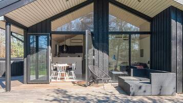 Uma casa moderna com varanda coberta, área de jantar e sala de estar com móveis para área externa.