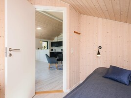 Un dormitorio con cama, una puerta que da a la cocina y una silla.