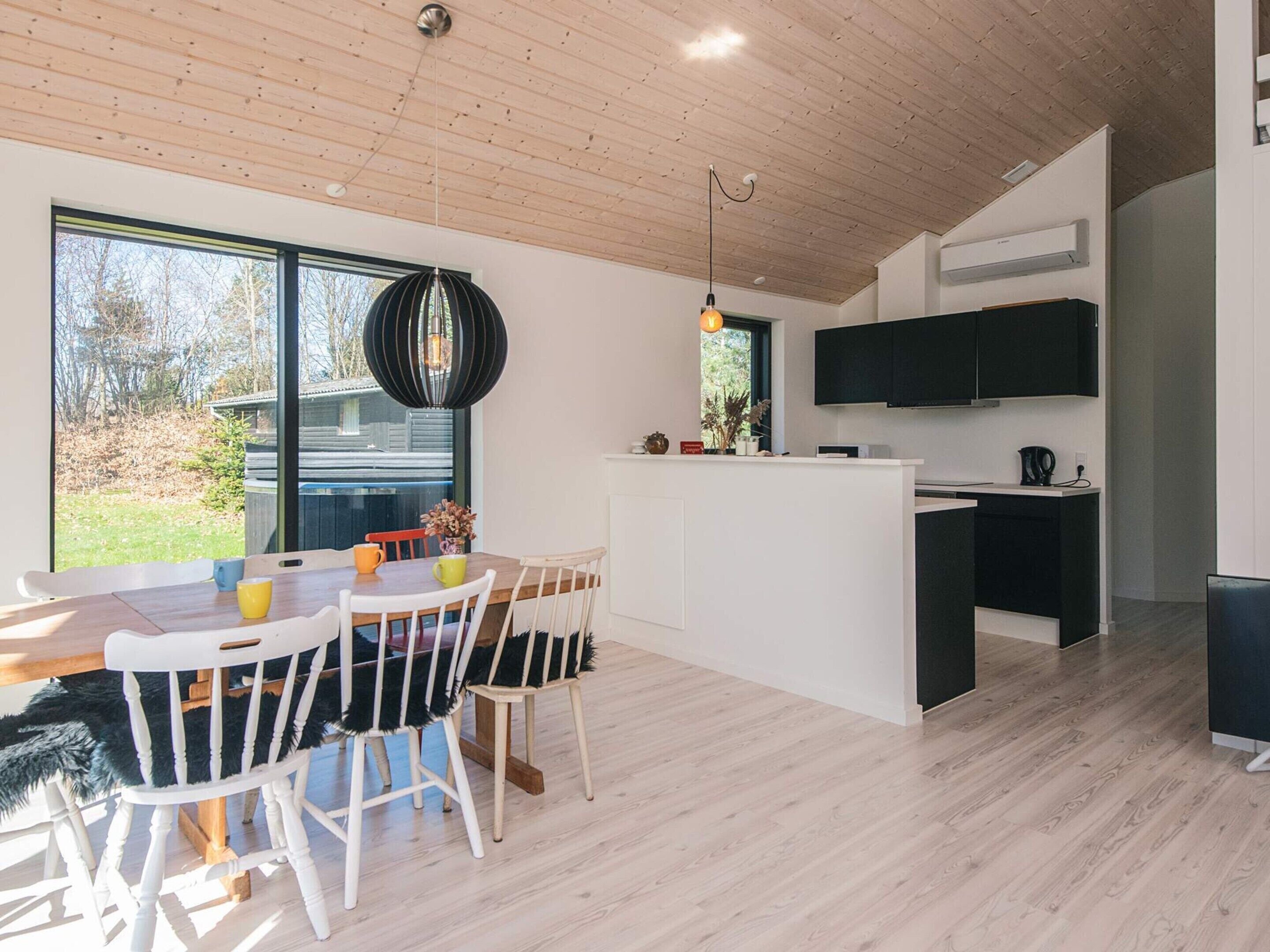 Cozinha moderna com uma ilha grande, armários brancos e uma televisão de tela plana.