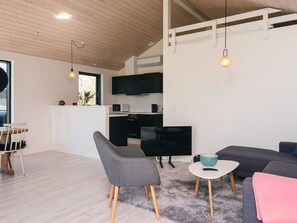 A modern interior with a kitchen, dining area, and living space, featuring wooden floors, a gray sofa, and pendant lighting. - 4 Star Holiday Home in Grenaa (Grenaa)