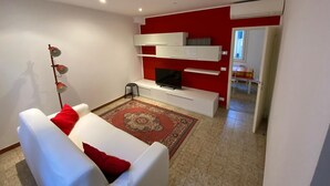 A modern living room with a white sofa, red cushions, a flat-screen TV, and a red accent wall. - Figher 795 ( near the Rialto Bridge ) (Venezia)