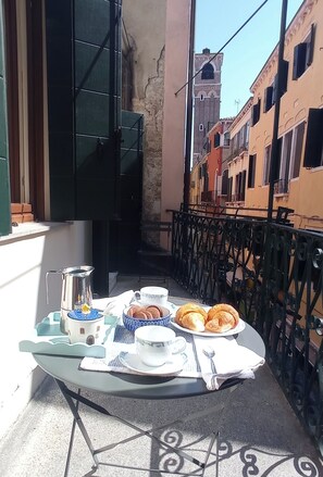 A balcony with a table set for breakfast, including croissants, coffee, and a teapot. - Figher 795 ( near the Rialto Bridge ) (Venezia)