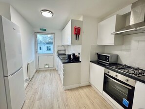 Eine moderne Küche mit weißen Schränken, einem Gasherd, einer Mikrowelle und einem Kühlschrank.