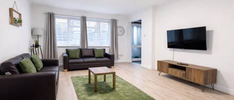 Una sala de estar moderna con un sofá, una mesa de centro, un televisor y un mueble de madera.