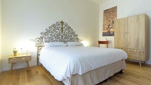 Ein Schlafzimmer mit einem Bett, einem Nachttisch, einem Holzschrank und einem Wandbild.