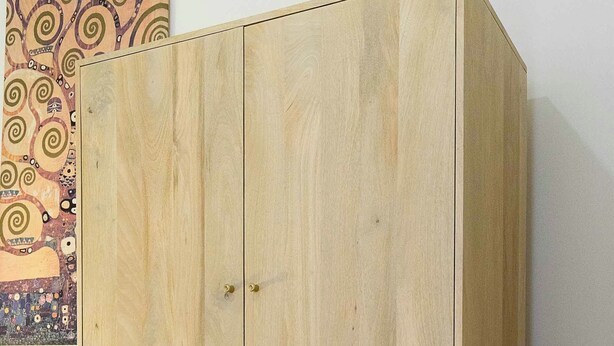 Ein Holzkleiderschrank mit zwei Türen und einer Schublade im unteren Bereich, verziert mit einem geometrischen Muster.