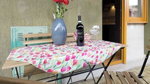 Eine Terrasse im Freien mit einem Tisch für zwei Personen, einer Blumenvase und einer Weinflasche.