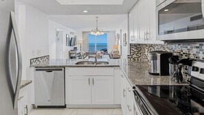 A modern kitchen with white cabinetry, a dishwasher, a double sink, and a black stove. - SC1-802 | Gulf-Front 3BR Condo • Direct Balcony Views (Indian Shores)