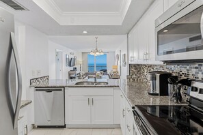 A modern kitchen with white cabinetry, a dishwasher, a double sink, and a black stove. - SC1-802 | Gulf-Front 3BR Condo • Direct Balcony Views (Indian Shores)