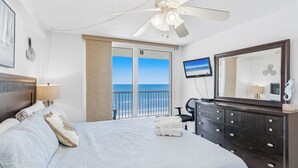 A bedroom with a bed, a dresser, a television, and a balcony with a view of the ocean. - SC1-802 | Gulf-Front 3BR Condo • Direct Balcony Views (Indian Shores)