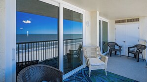 A balcony with a view of the ocean, featuring wicker chairs and a white door. - SC1-802 | Gulf-Front 3BR Condo • Direct Balcony Views (Indian Shores)