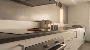 Una cocina moderna con horno integrado, cafetera y lavadora.