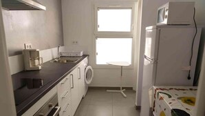Cocina compacta con lavadora, microondas y refrigerador.
