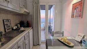 Eine Küche mit Meerblick, ein Essbereich mit Tisch und ein Balkon mit einem Stuhl.