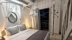 Ein Schlafzimmer mit Bett, Nachttisch, Lampe und Blick nach draußen.