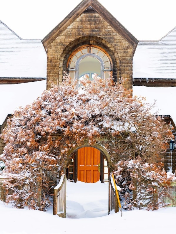 Un edificio cubierto de nieve con un arco de madera que conduce a una puerta roja.