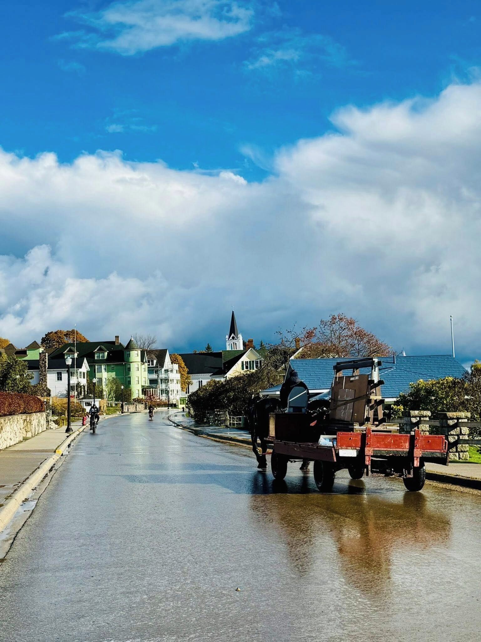 Eine Küstenstraße mit Pferdekutsche, Gebäuden und wolkenlosem Himmel.