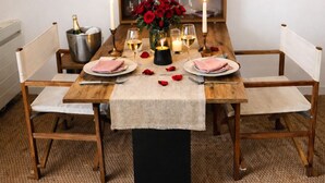 A dining table set with candles, glasses, and a vase of red roses. - Studio 180° sea view - Terrace - Sunset (Calais)
