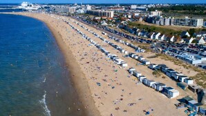 A beach with rows of beach huts and a large cruise ship docked nearby. - Studio 180° sea view - Terrace - Sunset (Calais)