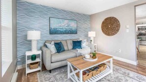 Een moderne woonkamer met een bank, salontafel en decoratieve muurkunst.
