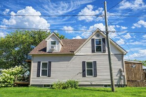 A two-story house with a gabled roof, a front porch, and a wooden fence.