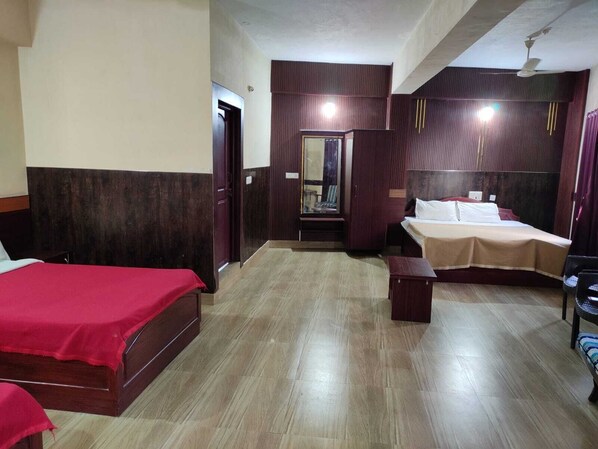 Una camera d'albergo con due letti, un armadio, uno specchio e una ventola a soffitto.