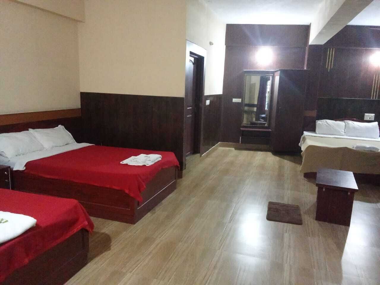 A hotel room with two beds, a wooden floor, and a mirror.