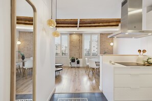 A modern kitchen with a large window, wooden ceiling beams, and a dining area with a view. - Comfort, style, and convenience all in one place!  ✨ - several units (Barcelona)